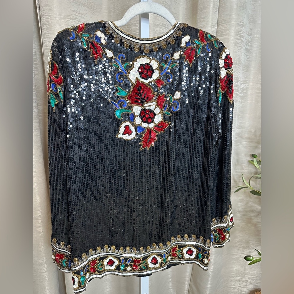 Vintage women’s black silk sequin evening jacket with red floral design.